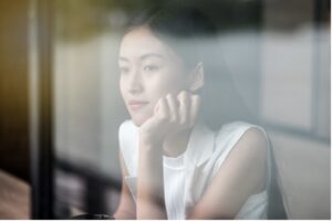 A young woman gazing thoughtfully out a window, reflecting on her next steps in life